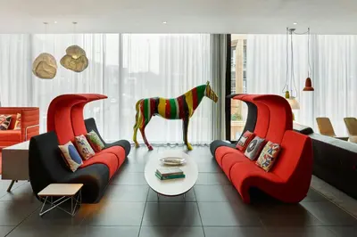 a living room with two red couches and a horse statue at citizenM Glasgow in Glasgow