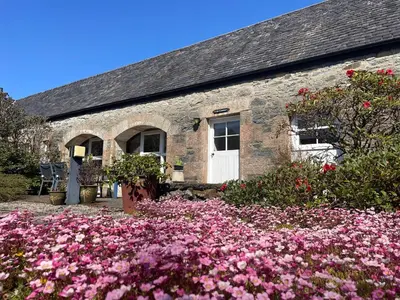 a stone house with pink flowers in front of it at The Steading at Barmore in Tarbert