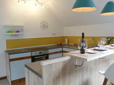 a kitchen with wooden cabinets and a table with a sink at The Steading at Barmore in Tarbert