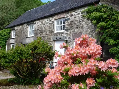 an old stone house with flowers in front of it at The Steading at Barmore in Tarbert