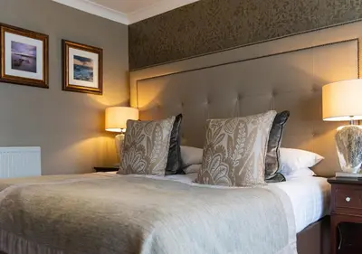 a bedroom with a large bed with two lamps at Piersland House in Troon