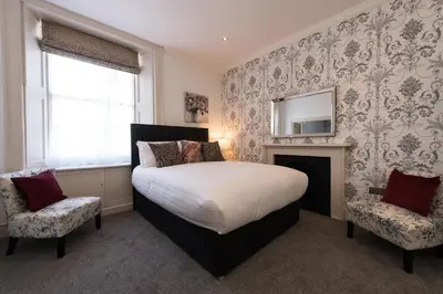 a bedroom with a bed and a fireplace and a mirror at Royal Princes Suites in Edinburgh