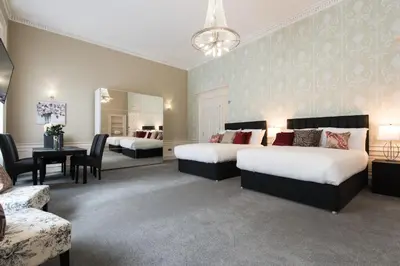 a bedroom with two beds and a table and chairs at Royal Princes Suites in Edinburgh