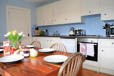 a kitchen with a wooden table with plates on it at Shelduck Cottage in Feorlean