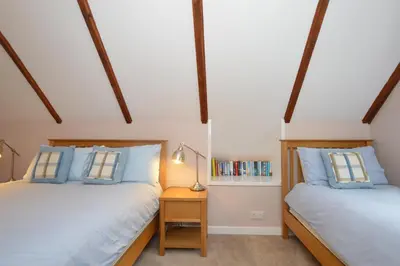 two twin beds in a room with wooden beams at Birch Cottage in Blairmore