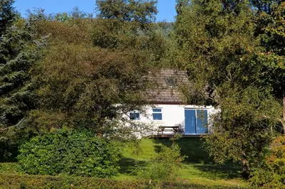 a white house in the middle of trees at Birch Cottage in Blairmore