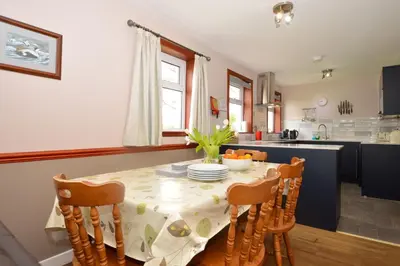 a kitchen with a table with chairs and a table and a kitchen with a kitchen at Birch Cottage in Blairmore