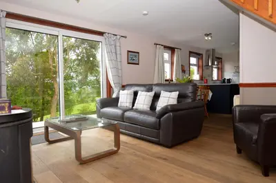 a living room with a leather couch and a table at Birch Cottage in Blairmore