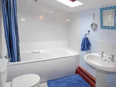 a bathroom with a tub and a toilet and a sink at Craigdarroch Cottage in Strathyre