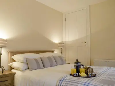 a white bed with a tray of food on it at Nether Cottage in Saline