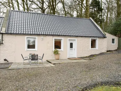 a small white house with a table and chairs at Kinneddar Cottage in Saline