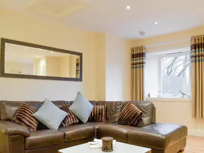 a living room with a brown leather couch and a mirror at Kinneddar Cottage in Saline