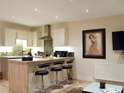 a kitchen with a counter and bar stools at Kinneddar Cottage in Saline