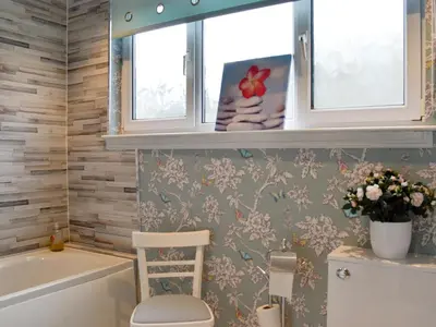a bathroom with a tub and a toilet and two windows at Park View Cottage in Stranraer