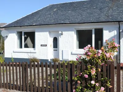 a white house with a fence and flowers at Rocky Mountain View in Ballachulish