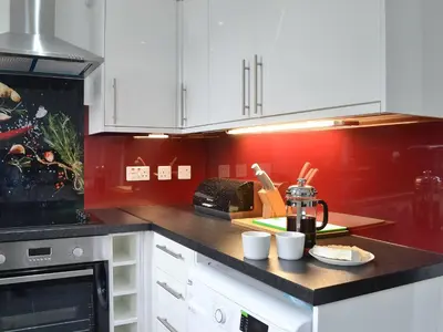 a kitchen with white cabinets and red walls at Rocky Mountain View in Ballachulish