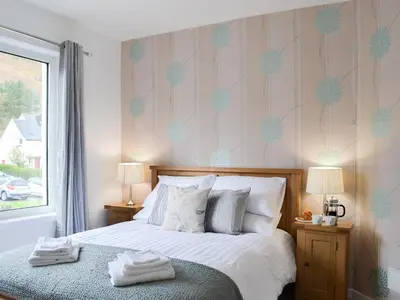 a bedroom with a bed with two lamps and a window at Rocky Mountain View in Ballachulish