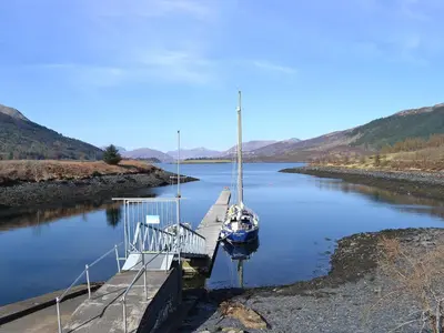 a boat is docked at a dock on a river at Rocky Mountain View in Ballachulish