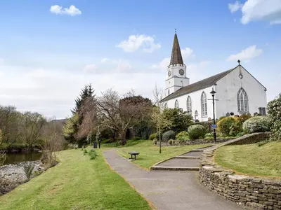 a church with a steeple and a walkway in front at Caroch Cottage in Comrie