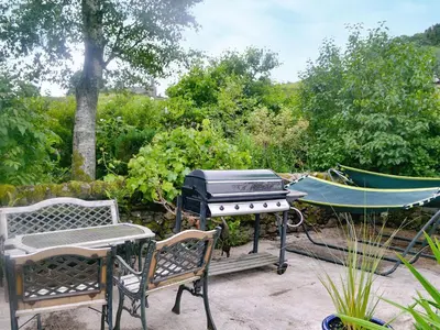 a grill and two chairs and a hammock on a patio at The Cottage in Blackwood