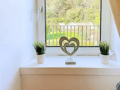 a window sill with two potted plants and a heart ornament at Thornbank in Millport