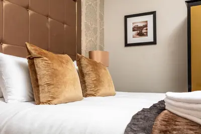 a bedroom with a bed with white sheets and gold pillows at The Kylestrome in Ayr