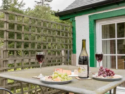 a table with two glasses of wine and plates of grapes at Bonnie's Bothy in Port of Menteith