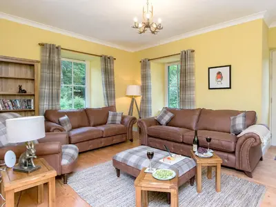 a living room with brown leather couches and tables at Grace's Cottage in Port of Menteith