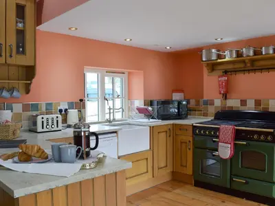 a kitchen with orange walls and a green oven at Grace's Cottage in Port of Menteith