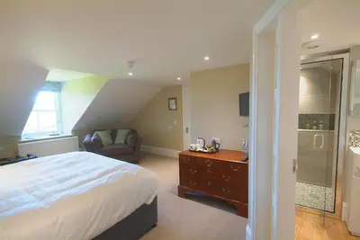a bedroom with a bed and a chair and a shower at Pennygate Lodge in Craignure
