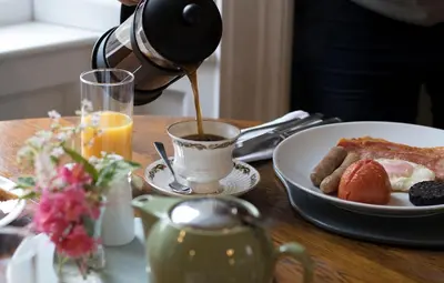 a person pouring coffee into a plate of breakfast food at Pennygate Lodge in Craignure