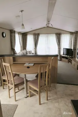 a dining room with a table and chairs and a television at West Loch Shores in Tarbert