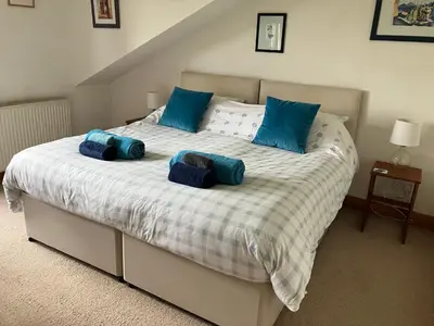a bedroom with a large bed with blue pillows at Midkinleith Farm Holiday Cottage in Edinburgh