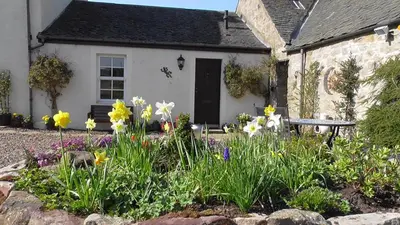 a house with a garden of flowers in front of it at Midkinleith Farm Holiday Cottage in Edinburgh