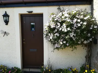 a door with flowers on the side of a house at Midkinleith Farm Holiday Cottage in Edinburgh