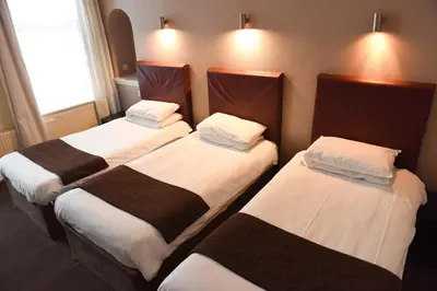 a group of three beds in a room at Sandyford Hotel in Glasgow