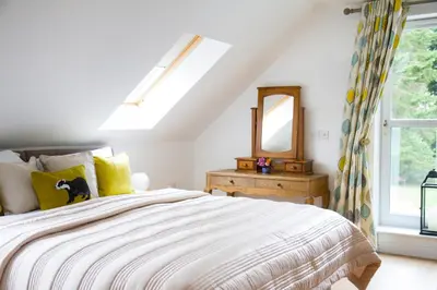 a bedroom with a bed with a mirror and a window at Badgers Den in Linlithgow