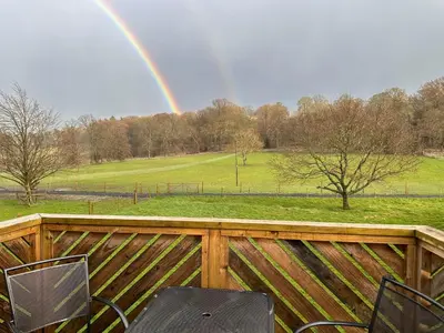 a rainbow over a yard with chairs and a fence at Badgers Den in Linlithgow