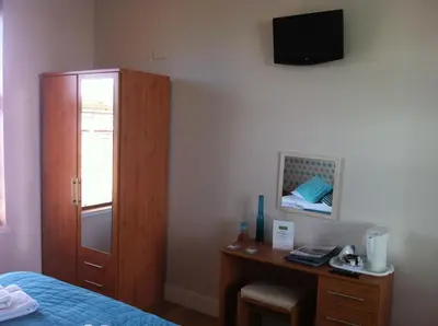a bedroom with a bed and a desk and a cabinet at Ashbank Bed & Breakfast in Drymen