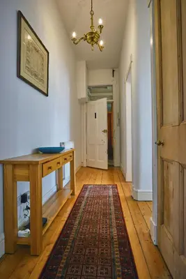a hallway with a wooden table and a rug at Comely Bank Apartment in Edinburgh