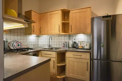a kitchen with wooden cabinets and a stainless steel refrigerator at Comely Bank Apartment in Edinburgh