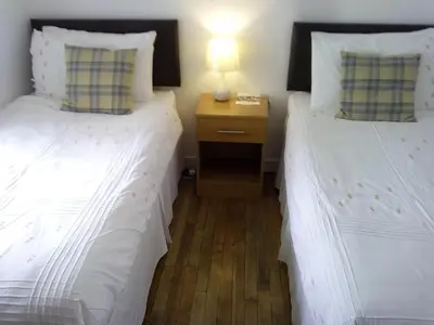 two twin beds in a room with a night stand at Starfish Rooms in Tarbert