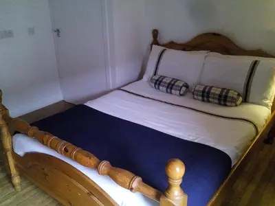 a wooden bed with two pillows on top of it at Starfish Rooms in Tarbert