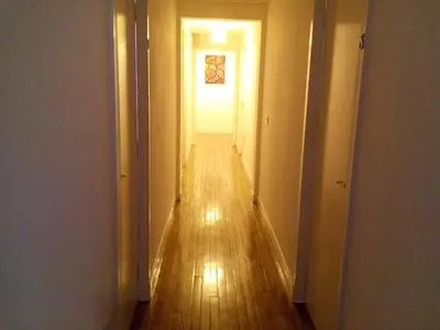 an empty hallway with a long wooden floor and a white door at Starfish Rooms in Tarbert