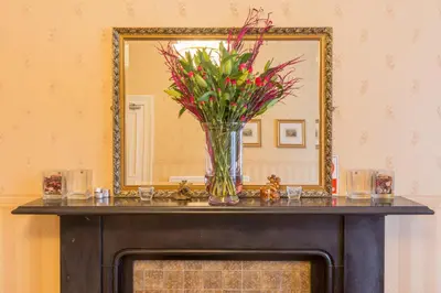 a vase of flowers on a table in front of a mirror at Menzies Guest House in Edinburgh