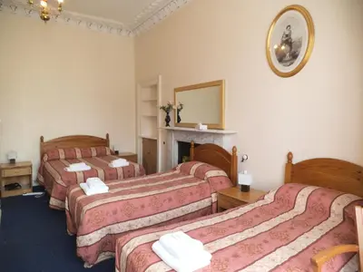 a hotel room with three beds and a fireplace at Menzies Guest House in Edinburgh