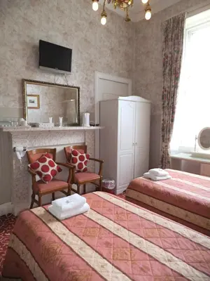 a hotel room with two beds and a mirror at Menzies Guest House in Edinburgh