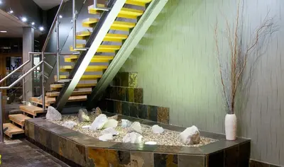 a lobby with a staircase with rocks and a vase at Castlecary House Hotel in Cumbernauld