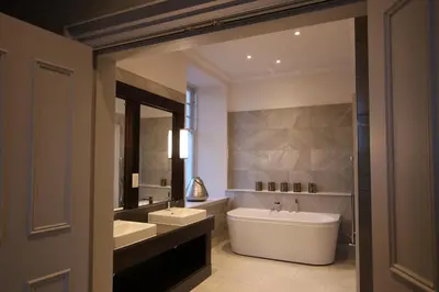 a bathroom with a large white tub and a sink and a mirror at Castlecary House Hotel in Cumbernauld