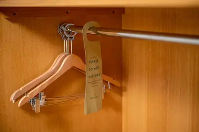 a closet with a hanger with a sign on it at The Titan By Greene King Inns in Clydebank